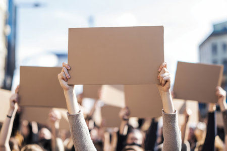 Demonstrators gather in an urban area, raising blank signs to express solidarity and social concerns.の写真素材