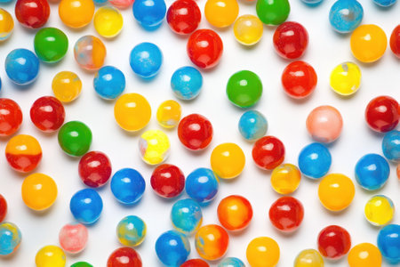 A variety of colorful jelly balls in red, blue, yellow, and green are scattered across a white background.の写真素材