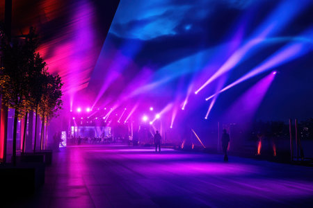 Bright purple and blue lights shine on a spacious area with people gathered at sunset near the water.の写真素材