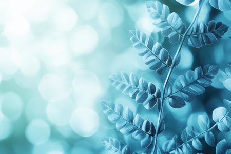 Delicate fern leaves stand out vividly against a blue bokeh background, creating a serene atmosphere.の写真素材