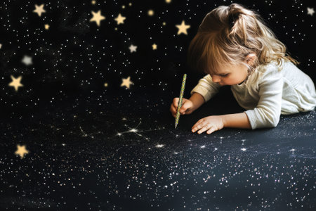 Young child enjoying creative activity by drawing stars on a dark surface using a glitter pen.の写真素材