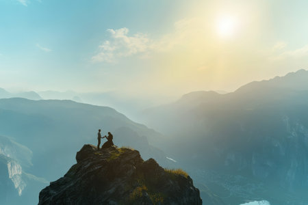 A couple stands on a mountain peak, embracing while enjoying the beautiful sunset and panoramic views.の写真素材