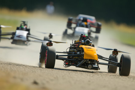High-speed racing drones maneuver aggressively on a dirt track under clear skies on an autumn day.の写真素材