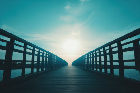 A wooden bridge extends over calm waters towards a luminous horizon, creating a peaceful atmosphere at dusk.の写真素材