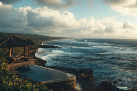 This stunning coastal vista features a tranquil pool next to rocky shores with crashing waves and distant hills.の写真素材