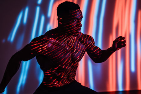 A strong dancer captures movement amidst vibrant red and blue lights in a stylish studio setting.の写真素材