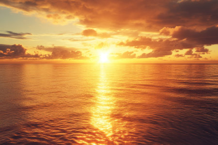 A serene sunset paints the sky in warm hues, casting brilliant reflections on the tranquil ocean waters.の写真素材