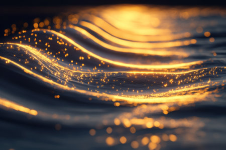 Golden sunlight glistens on soft waves as they gently roll, creating a serene atmosphere at sunset.の写真素材