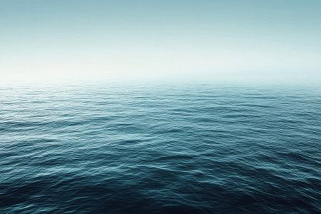Gentle waves roll across a serene ocean as daylight softly fades into evening, creating a tranquil atmosphere.の写真素材