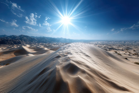 Golden sand rises in gentle dunes under a brilliant sun illuminating the expansive desert landscape.の写真素材