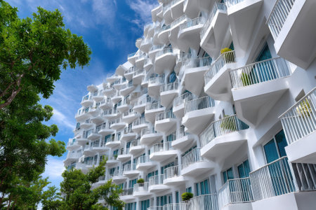 A unique white building displays modern architecture with curved balconies under a bright blue sky.の写真素材