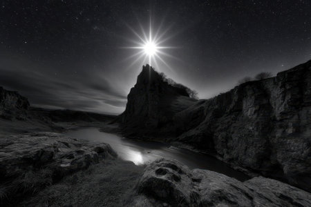 Night sky illuminated by a bright starburst above towering cliffs and a peaceful river reflecting light.の写真素材