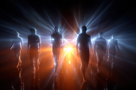 Silhouetted figures walk towards a bright light source, creating an ethereal atmosphere in darkness.の写真素材