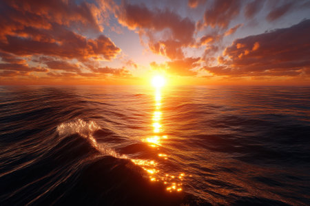 Warm sunlight illuminates the horizon as it sets over the calm ocean waters, creating a serene atmosphere.の写真素材