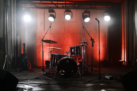 Lighting creates an energetic atmosphere around the empty drum set waiting for musicians to start playing.の写真素材