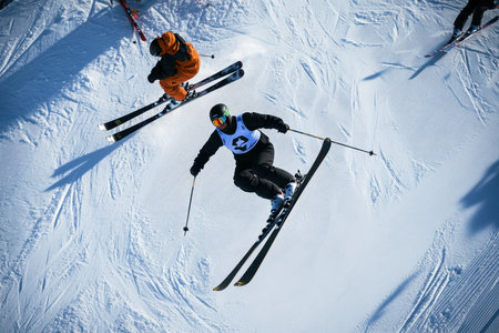 Two skiers showcase impressive aerial maneuvers on a snowy slope during a winter sports event.の写真素材
