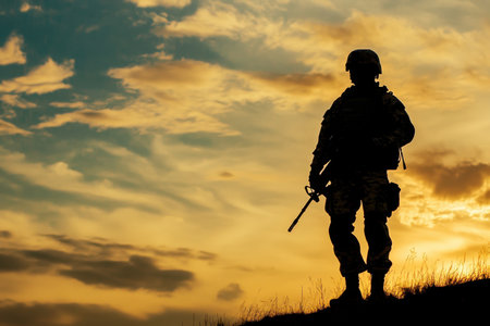 A soldier stands alone holding a weapon as the sun sets, creating a dramatic sky filled with colors.の写真素材