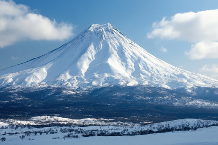A towering snow-capped volcano stands against a bright sky, surrounded by untouched winter scenery.の写真素材
