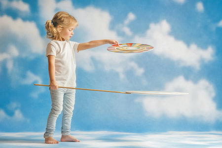 A child balances colorful spinning discs while standing barefoot on a soft surface, enjoying playful creativity.の写真素材