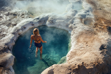A woman enjoys a soak in a warm hot spring surrounded by steamy minerals, embracing nature's tranquility.の写真素材