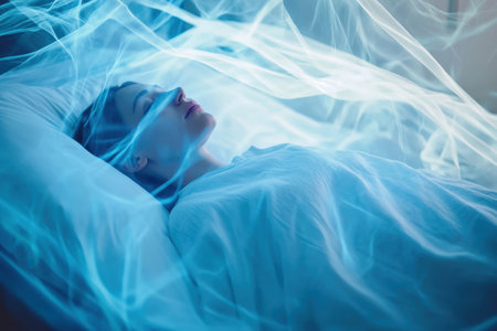 A woman rests peacefully in bed enveloped by swirling blue light, creating a calm and dreamlike environment.の写真素材