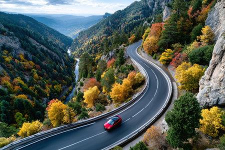 Aerial view of a red car on a winding mountain road in autumnの写真素材
