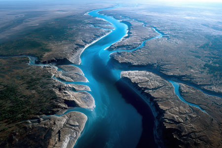 An aerial view of a vibrant blue river carving its way through a vast desert canyonの写真素材