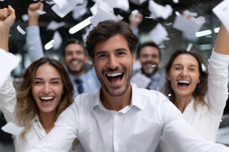 A group of enthusiastic professionals celebrates a significant achievement in a contemporary office environment.の素材