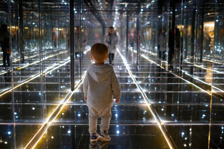 A young child wanders through a maze of mirrors, captivated by the endless reflections and lights.の写真素材