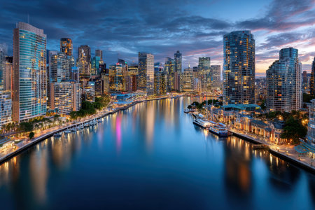 A cityscape with illuminated buildings along a river at duskの写真素材