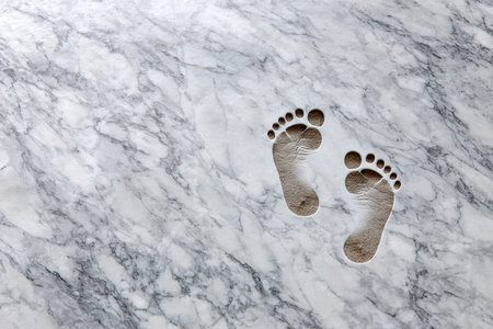 Footprints are visible on a smooth marble surface, highlighting a unique and artistic pattern in a clean area.の写真素材