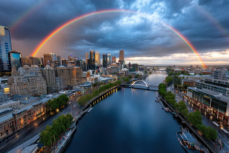 Aerial view of a cityscape with a river and a double rainbow at duskの写真素材