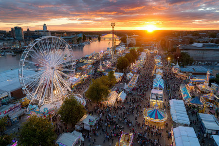 A bustling carnival at sunset, lit by the golden hour light, shot with a drone camera, featuring a man winning a giant prizeの写真素材
