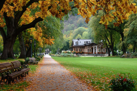 A paved path winds through a park filled with autumn leaves and treesの写真素材