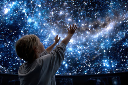 A young child reaches out to a mesmerizing display of stars and galaxies in a planetarium.の写真素材