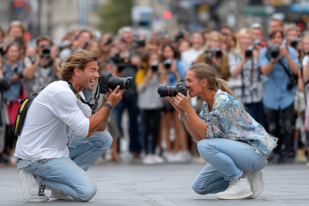 Two photographers capturing images of a crowd at an outdoor eventの写真素材