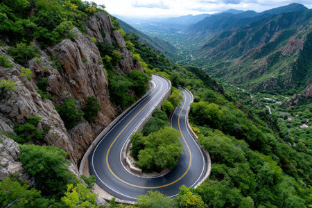 A winding mountain road snakes through a lush green valleyの素材