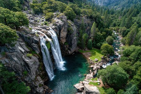 A waterfall cascades into a pool in a forested valleyの素材