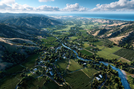 An aerial shot of a green valley and river meeting the ocean and mountainsの写真素材
