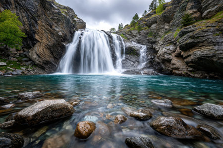 A waterfall cascades into a turquoise river surrounded by rocks and foliageの写真素材