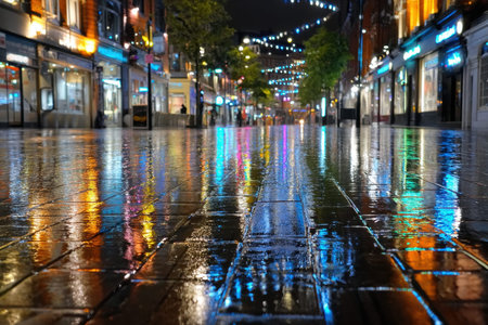 Wet pavement reflects colorful lights on a rainy city street at nightの写真素材