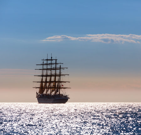 The world's largest sailing ship with five masts leaves at sunset in the open sea.