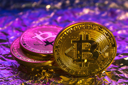 Cryptocurrency physical golden bitcoin coin on colorful backgroundの写真素材