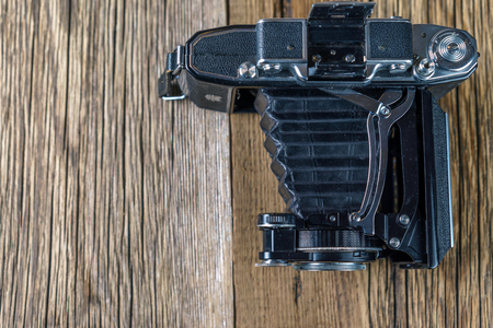 old folding camera on a textured rustic wooden surface.の写真素材