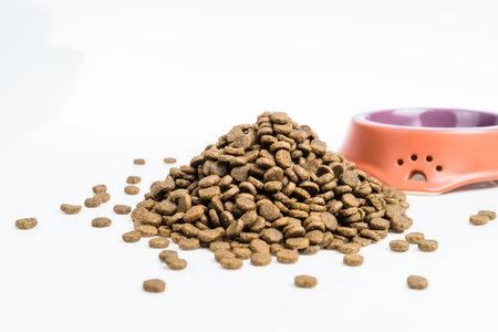 Dry pets food on white background, bowl in the backgroundの写真素材