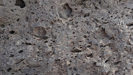 Close-up of a stone wall with cracks and holes in itの写真素材