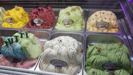 A variety of ice cream flavors on display in a shop window.