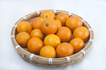 Orange in a bamboo basket isolated on white background の写真素材