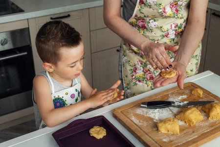 Cute little boy helps her mother prepare cookies