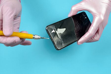 Close-up shot of hands opening broken mobile with screwdriverの写真素材